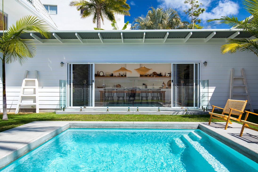 a white beach house with a pool in front of it